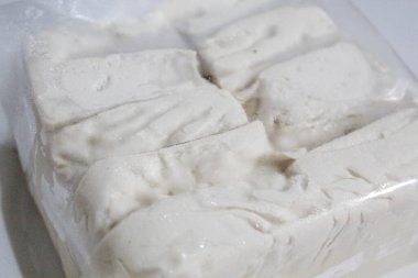 Bir paket ipeksi süt tofu, pişmemiş, beyaz arka planda izole edilmiş.
