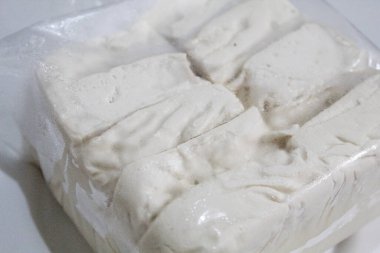 Bir paket ipeksi süt tofu, pişmemiş, beyaz arka planda izole edilmiş.