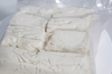 Bir paket ipeksi süt tofu, pişmemiş, beyaz arka planda izole edilmiş.