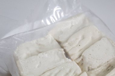 Bir paket ipeksi süt tofu, pişmemiş, beyaz arka planda izole edilmiş.