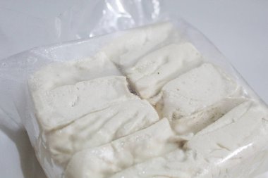 Bir paket ipeksi süt tofu, pişmemiş, beyaz arka planda izole edilmiş.
