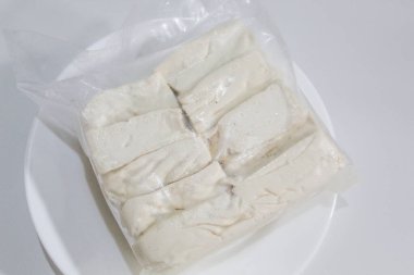 Bir paket ipeksi süt tofu, pişmemiş, beyaz arka planda izole edilmiş.