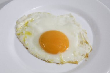 Kızarmış yumurta ya da beyaz bir tabakta güneşli tarafı. Ortadaki turuncu yumurta sarısı. Beyaz arkaplanda izole