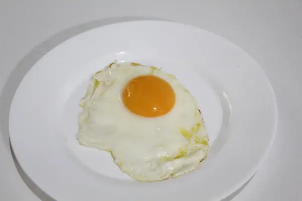 Kızarmış yumurta ya da beyaz bir tabakta güneşli tarafı. Ortadaki turuncu yumurta sarısı. Beyaz arkaplanda izole