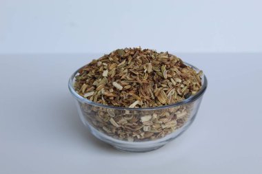 Dried granules of Aniseed, or Pimpinella Anisum seed, or Adas Manis, inside a bowl. Isolated on white background clipart