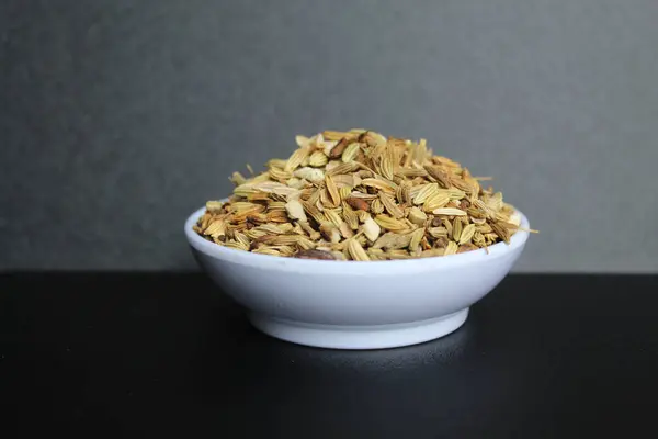 Aniseed 'in kurumuş granülleri, ya da Pimpinella Anisum tohumu, ya da Adas Manis, bir kasenin içinde. Siyah arkaplanda izole