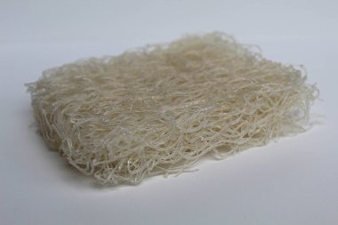 Pişmemiş kare şeklinde pirinç vermicelli ya da pirinç eriştesi, beyaz arka planda izole edilmiş.