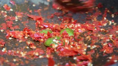 Asyalı bir el kırmızı biber ve kireçle taş havan ve tokmakla vuruyor. Bir Endonezya yemek çeşnisi olan sambal yapma süreci