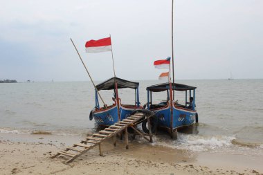 Endonezya bayrağı dalgalanarak Teluk Awur Sahili 'ne eğilen geleneksel mavi balıkçı teknesi. 24 Eylül 2022 'de Jepara, Endonezya