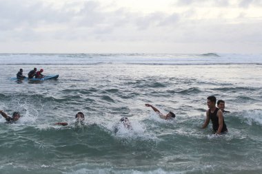 Asyalı çocuklar dalgaların arasında eğleniyor. 8 Ekim 2022 'de Yogyakarta, Endonezya