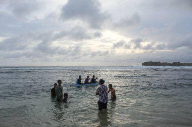 Asyalı çocuklar dalgaların arasında eğleniyor. 8 Ekim 2022 'de Yogyakarta, Endonezya