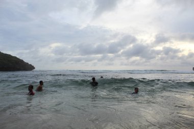 Asyalı çocuklar dalgaların arasında eğleniyor. 8 Ekim 2022 'de Yogyakarta, Endonezya