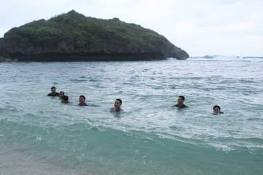 Asyalı çocuklar dalgaların arasında eğleniyor. 8 Ekim 2022 'de Yogyakarta, Endonezya