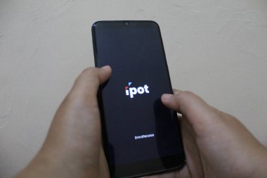 Semarang, Indonesia - November 27th 2022: IPOT app logo display on a smartphone. IPOT app by Indo Premier Investment from Indonesia clipart