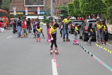 Asyalı çocuklar paten oynuyorlar, bardakları sokağa koyuyorlar. 12 Nisan 2022 'de Semarang, Endonezya