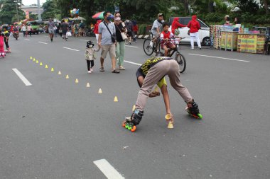 Asyalı çocuklar paten oynuyorlar, bardakları sokağa koyuyorlar. 12 Nisan 2022 'de Semarang, Endonezya