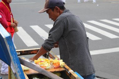 Sokak satıcıları rujak buah veya geleneksel meyve salatası satıyorlar. 12 Nisan 2022 'de Semarang, Endonezya