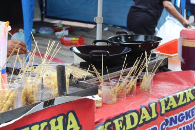 Sokak satıcısı telur gulung satıyor. Kızarmış yumurtadan yapılmış abur cubur. Çubuğa sarılmış.