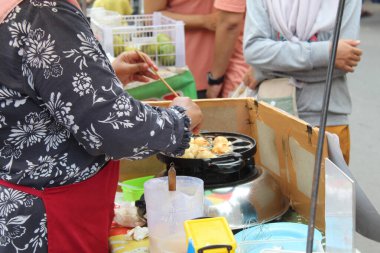 Sokak satıcısı takoyaki pişiriyor ve satıyor, Japon yemekleri.