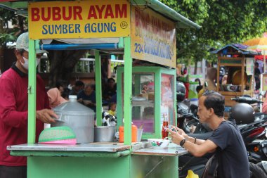 Sokak satıcısı bubur ayam veya geleneksel alışveriş arabasıyla tavuk lapası satıyor. 12 Nisan 2022 'de Semarang, Endonezya