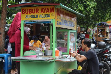 Sokak satıcısı bubur ayam veya geleneksel alışveriş arabasıyla tavuk lapası satıyor. 12 Nisan 2022 'de Semarang, Endonezya