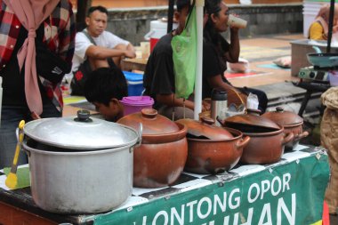 Sokak satıcısı çömlek konteynırıyla yemek satıyor. 12 Nisan 2024 'te Semarang, Endonezya