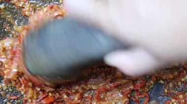 Kırmızı biber, soğan, sarımsak ve domates ezen Asyalı bir el. Saman ağacını yapma süreci, Endonezya baharatlı besin.