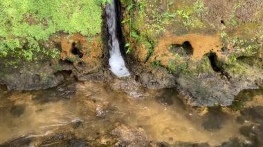 Su kanalından nehre küçük bir şelale. Yerdeki delikten akan su.