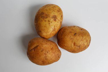 Soyulmamış üç patates, beyaz arka planda izole edilmiş.