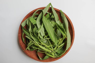 Toplanan su ıspanağı yaprakları, ahşap tabakta, beyaz arka planda izole, düz ya da üst görünümde