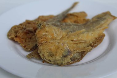 Kızarmış balık. Endonezya 'da Gereh veya Ikan Asin olarak adlandırılan tuzlama yöntemi, yarısı kesilmiş un kaplı balıkları korudu. Beyaz arkaplanda izole