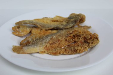 Fried fish. Preserved fish by salting method, half cut, flour coated, called Gereh or Ikan Asin in Indonesia. Isolated on white background clipart