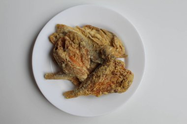 Fried fish. Preserved fish by salting method, half cut, flour coated, called Gereh or Ikan Asin in Indonesia. Isolated on white background, on white plate, flat lay or top view clipart