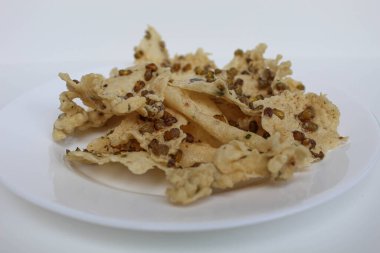 Geleneksel krakerler Endonezya 'dan geliyor, adı Rempeyek Kacang Hijau. Beyaz plaka üzerinde, beyaz arka planda izole edilmiş