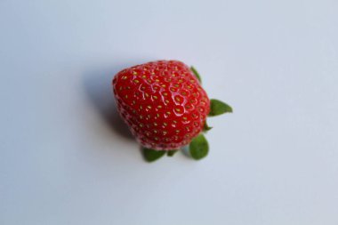 Yeşil saplı bir kırmızı çilek, beyaz arka planda izole edilmiş.