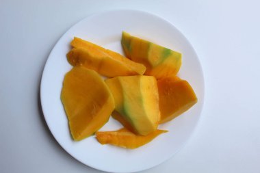Taze sarı mango dilimleri, beyaz tabakta, beyaz arkaplanda izole, düz ya da üst görünümde.