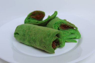 Dadar Gulung Isi Kelapa, Endonezya 'dan geleneksel tatlı. Yeşil renkli rulo krep, rendelenmiş hindistan cevizi ve kırmızı şeker. Beyaz bir plaka üzerinde, beyaz arka planda izole edilmiş.