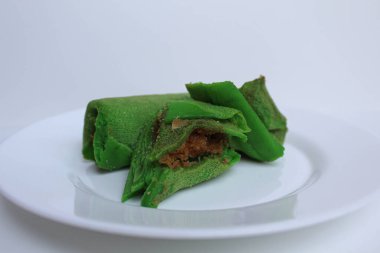 Dadar Gulung Isi Kelapa, Endonezya 'dan geleneksel tatlı. Yeşil renkli rulo krep, rendelenmiş hindistan cevizi ve kırmızı şeker. Beyaz bir plaka üzerinde, beyaz arka planda izole edilmiş.