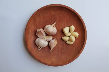 Sarımsak karanfili ya da soğan, soyulmadan önce ve sonra, ahşap tabakta, beyaz arka planda izole edilmiş, düz ya da üst görünümde