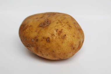 Bir patates soyulmamış, beyaz arka planda izole edilmiş.