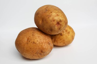Soyulmamış üç patates, beyaz arka planda izole edilmiş.