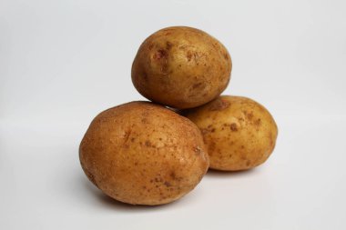 Soyulmamış üç patates, beyaz arka planda izole edilmiş.