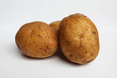 Soyulmamış üç patates, beyaz arka planda izole edilmiş.