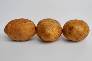 Three potatoes unpeeled, isolated on white background clipart