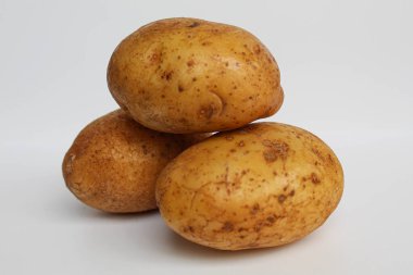 Soyulmamış üç patates, beyaz arka planda izole edilmiş.
