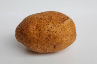 Bir patates soyulmamış, beyaz arka planda izole edilmiş.