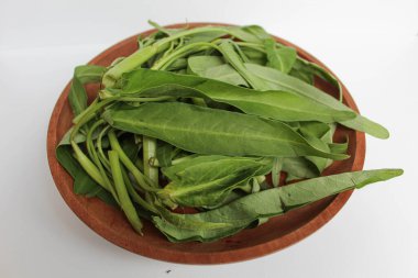 Tahta tabakta toplanmış su ıspanağı yaprakları, beyaz arka planda izole edilmiş.