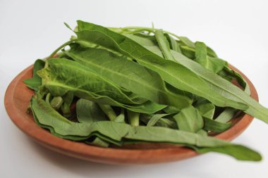 Tahta tabakta toplanmış su ıspanağı yaprakları, beyaz arka planda izole edilmiş.