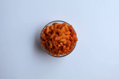 Baharatlı küçük makarna krakerleri, cam kasenin içinde, beyaz arka planda, düz yerde ya da üst tarafta.