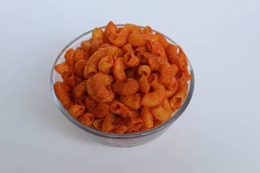 Spicy fried small macaroni crackers, inside glass bowl, on white background clipart